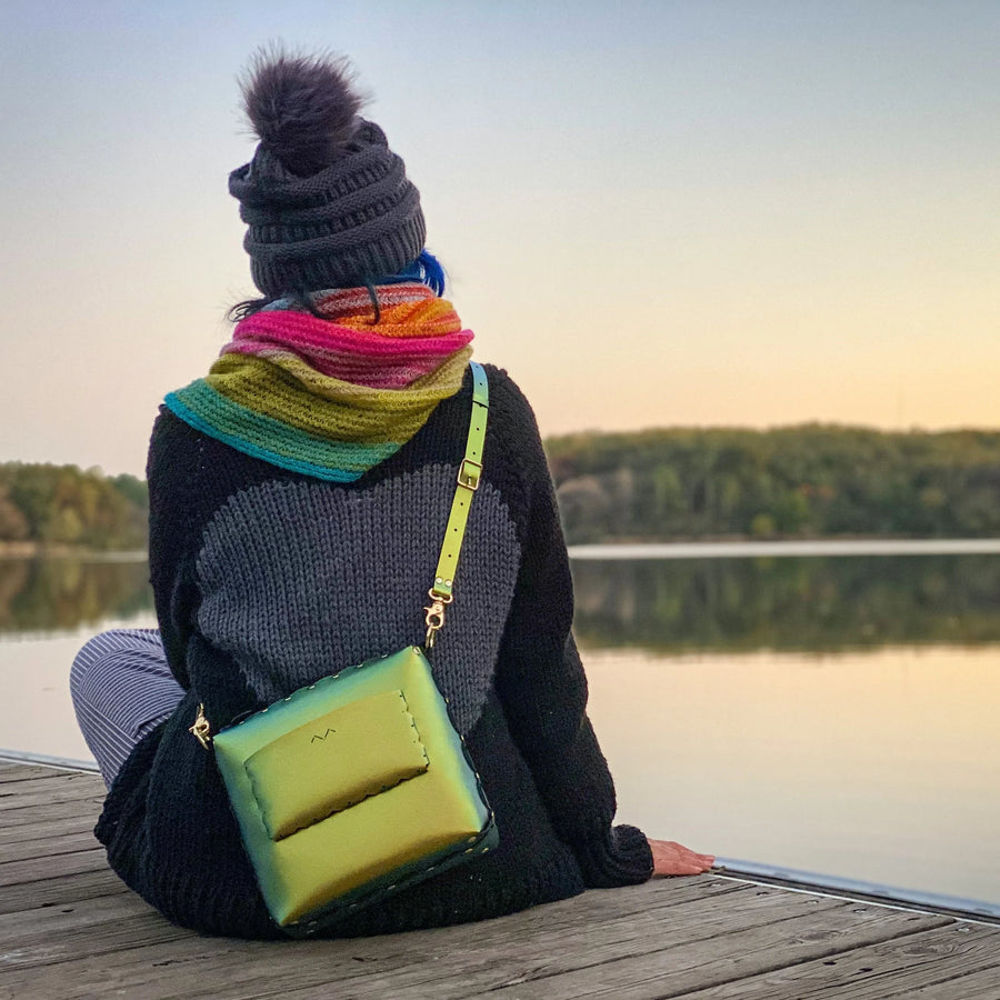 woman with scarab medium crossbody bag sitting dockside at sunset