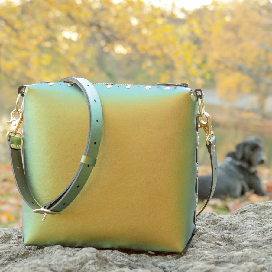 Scarab medium crossbody bag posed on rock during fall season